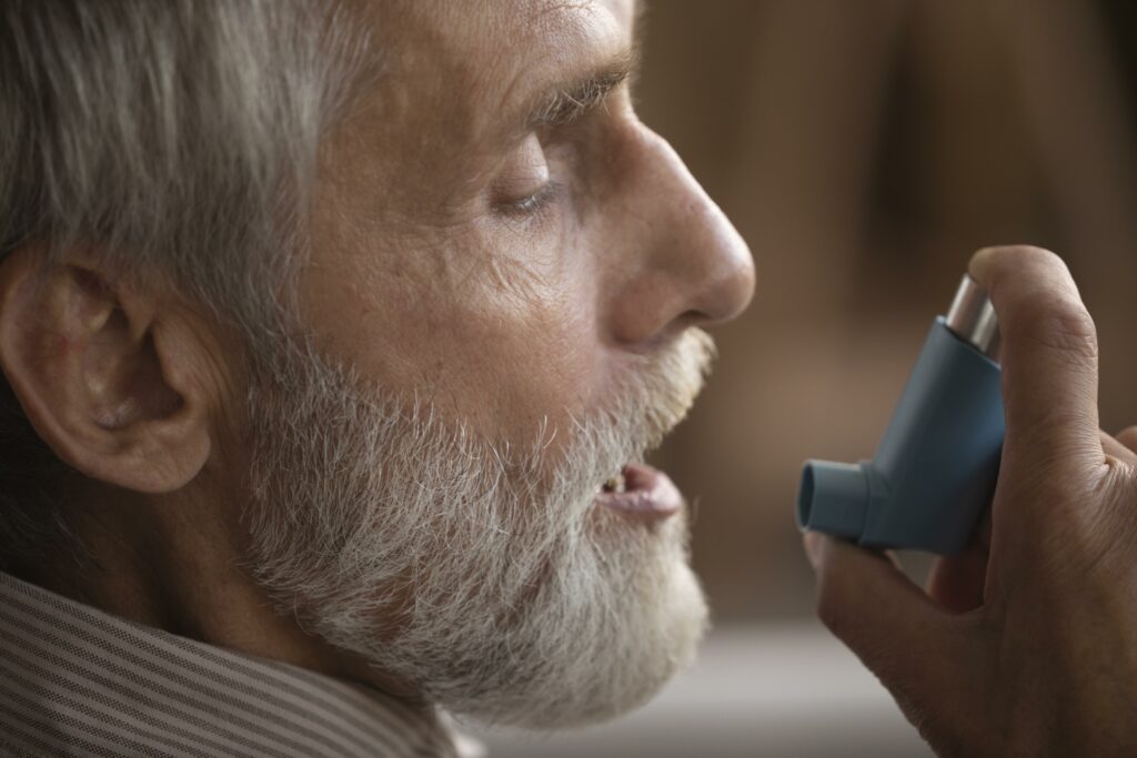 close up elderly man holding asthma inhaler