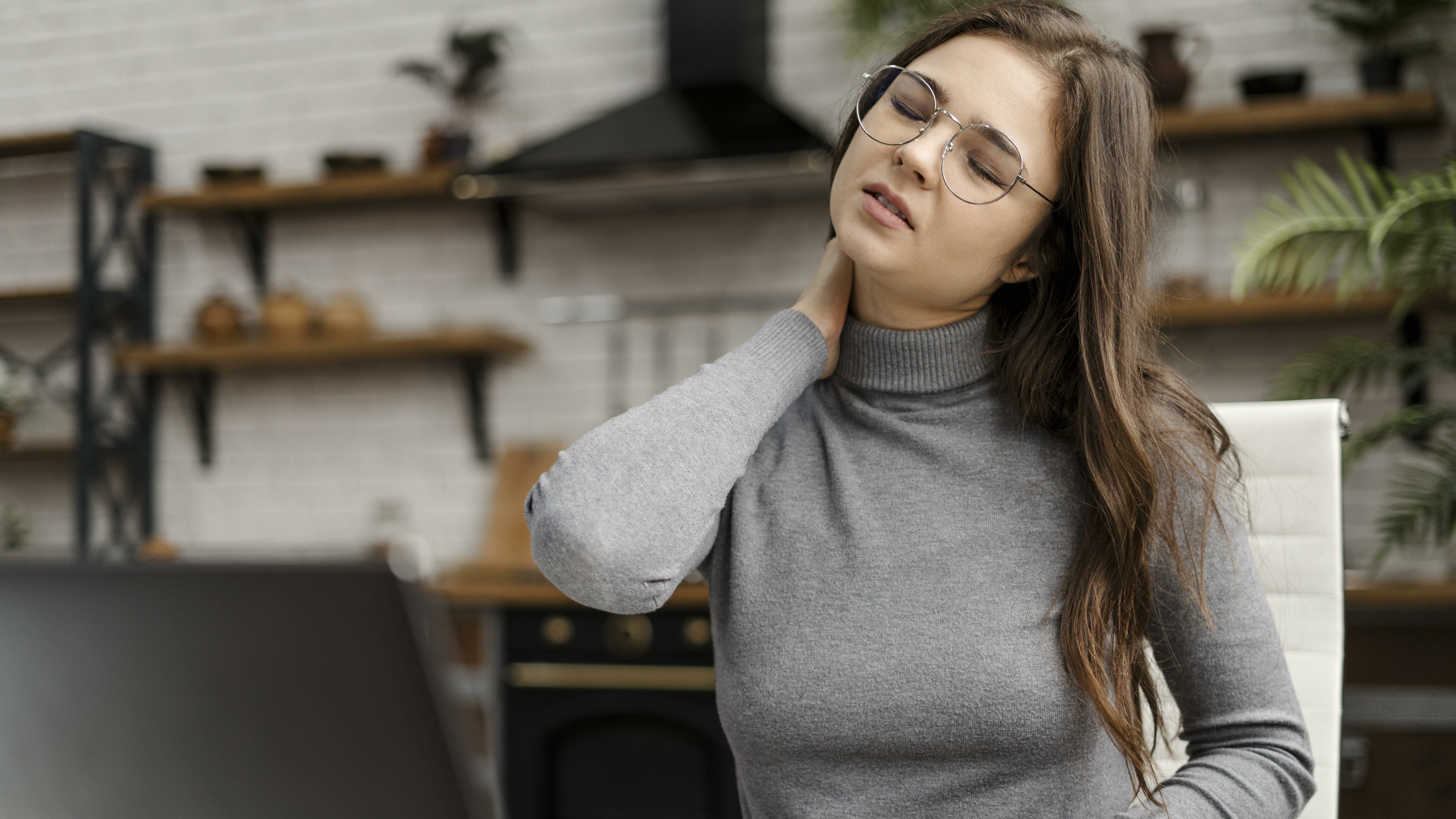 young woman having neckache while working from home edited